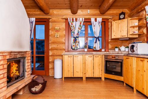 a kitchen with a fireplace in a log cabin at Chata na brehu Liptovskej Mary in Bobrovník