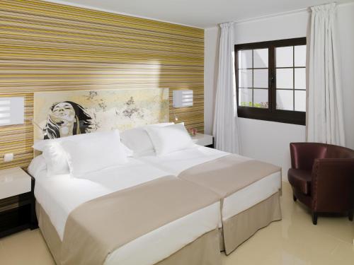 1 dormitorio con 1 cama blanca grande y 1 silla en Boutique Hotel H10 White Suites - Adults Only, en Playa Blanca