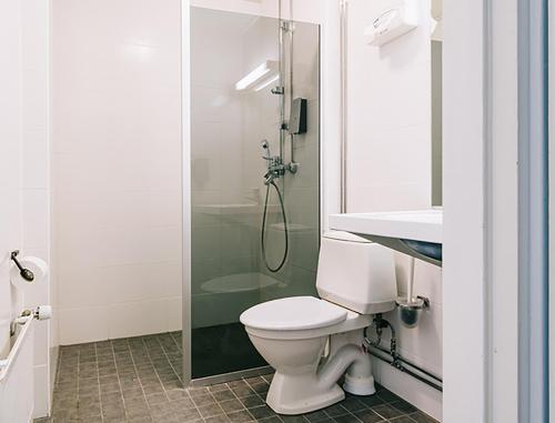 uma casa de banho com um WC e uma cabina de duche em vidro. em Comfort Guesthouse em Pietarsaari