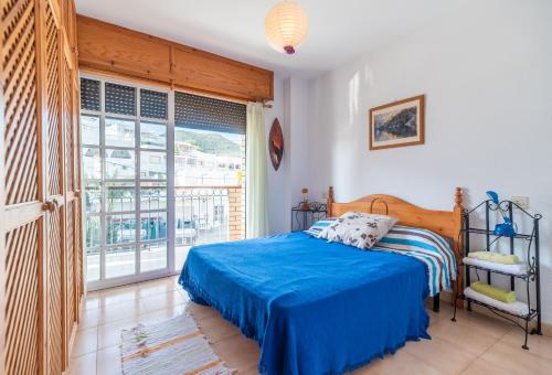 a bedroom with a blue bed and a large window at Apartamento del Mar San Jose in San José