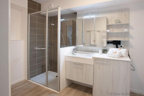 La salle de bains est pourvue d'un lavabo et d'une douche en verre. dans l'établissement DOMITYS - Les Papillons d'Azur, à Saint-Quentin