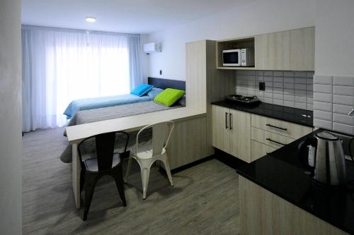 um pequeno quarto com uma cama e uma cozinha em Quijano Hotel - Aparts & Suites em Montevidéu