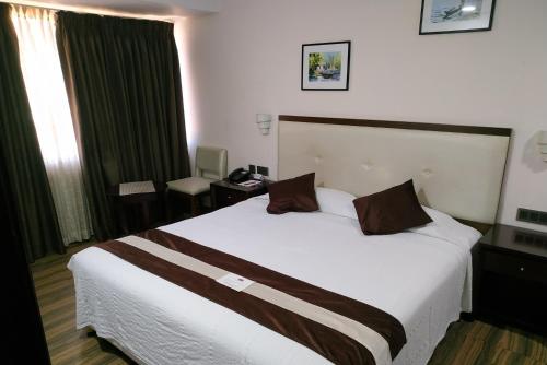 a hotel room with a large white bed with brown pillows at KGA Elite Continental Hotel in Thiruvalla