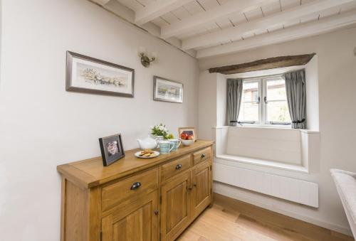 a room with a wooden dresser and a window at Vicarage Cottage in Powerstock