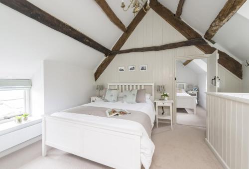 a white bedroom with a bed and a window at Vicarage Cottage in Powerstock