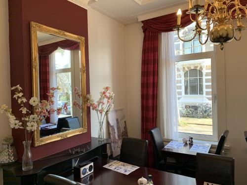 a dining room with a table and a mirror at Hotel Oorsprongpark in Utrecht