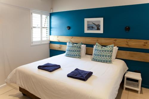 a bedroom with a large white bed with blue walls at Plett Beachfront Accommodation in Plettenberg Bay