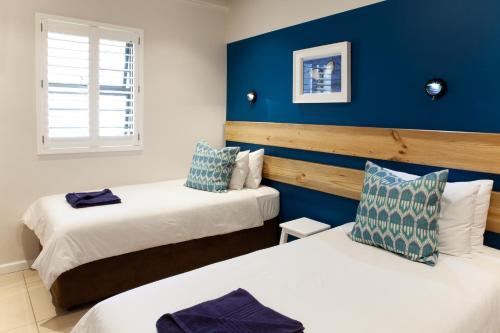 two beds in a room with blue walls at Plett Beachfront Accommodation in Plettenberg Bay
