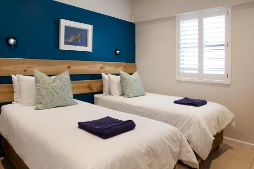 two beds in a room with blue walls at Plett Beachfront Accommodation in Plettenberg Bay