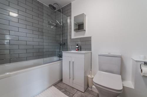 y baño con aseo, bañera y lavamanos. en Glastonbury Town Apartment, en Glastonbury