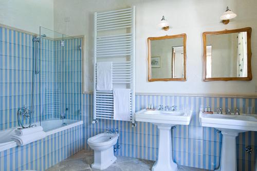 a blue and white bathroom with two sinks and a toilet at Villa de' Ricci Rignana B&B in Greve in Chianti