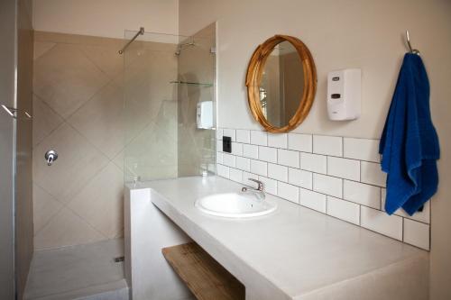a white bathroom with a sink and a mirror at Plett Beachfront Accommodation in Plettenberg Bay