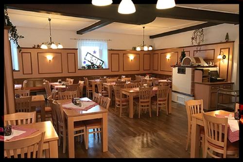 a restaurant with wooden tables and chairs and a kitchen at Landgasthof-Hotel Hammermühle in Donaustauf