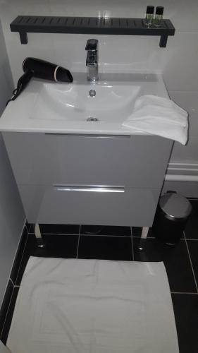 a white sink in a bathroom with a black floor at Hôtel Restaurant le clos de l 'Ancien Pressoir in Commes