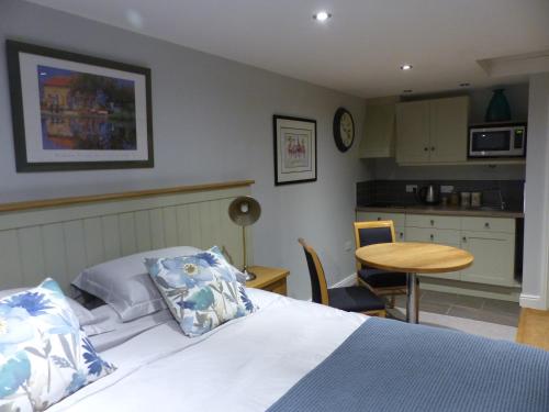 a bedroom with a bed and a table and a kitchen at Bed and Breakfast accommodation near Brinkley ideal for Newmarket and Cambridge in Newmarket
