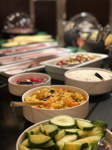 a table topped with bowls of food and cucumbers at Seminaris Hotel Lüneburg in Lüneburg