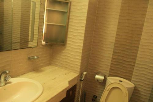 ein Badezimmer mit einem Waschbecken, einem WC und einem Spiegel in der Unterkunft Impressa on Shah in Dhaka