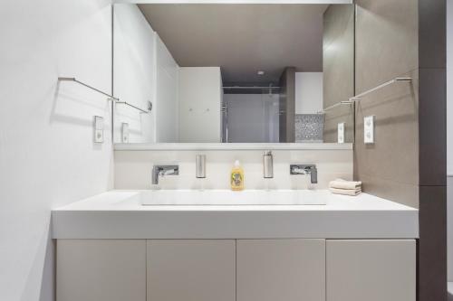 a white bathroom with a sink and a mirror at HHBCN Beach Apartment Gava #2 in Gavà