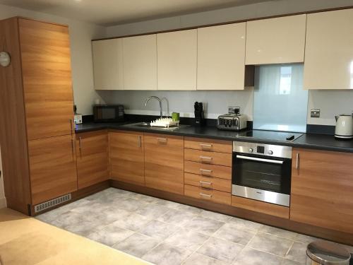 a kitchen with wooden cabinets and a stove at Toothbrush Apartments - Ipswich Waterfront - The Cambria in Ipswich