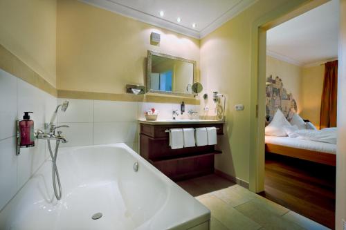 a bathroom with a bath tub and a bed at Simones Hotel Fürstenhof in Landshut