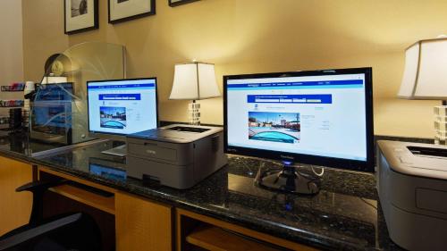 a desk with two computer monitors and a printer at Best Western Pasadena Inn in Pasadena