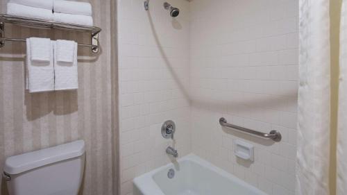 a bathroom with a toilet and a shower with towels at Best Western Pasadena Inn in Pasadena