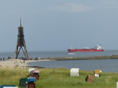 a large red ship in the water with a beach at Hotel Deichgraf in Cuxhaven