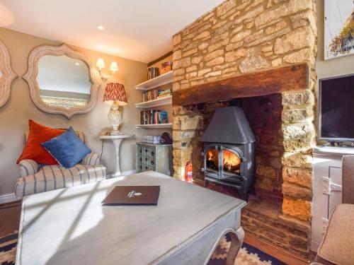 sala de estar con chimenea de piedra y fogones en Appletree Cottage en Bourton on the Water