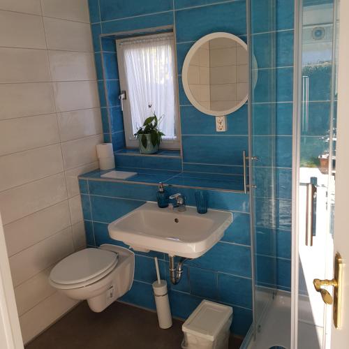 uma casa de banho em azulejos azuis com um WC e um lavatório em Bungalow Streuwiese em Warnemünde