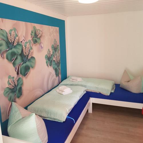 duas camas num quarto com uma parede com plantas em Bungalow Streuwiese em Warnemünde