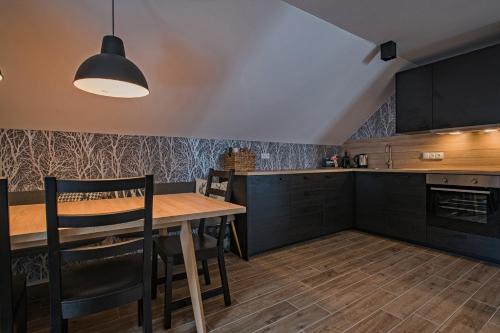a kitchen with a wooden table and black cabinets at Ruprecht Apartment in Vrchlabí