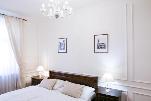 a bedroom with a bed with two night stands and two lamps at White & Gray Apartments in Prague