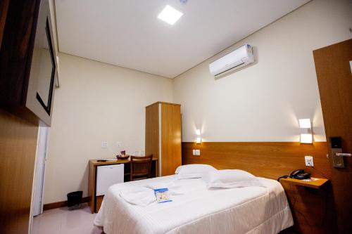 a bedroom with a white bed and a desk at Ipê Palace Hotel in Adamantina