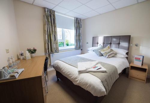 a bedroom with a large bed with a desk and a window at Lancaster University in Lancaster