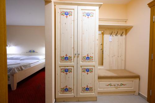 a bedroom with a large white cabinet with flowers on it at Hotel Julianin dvor in Habovka