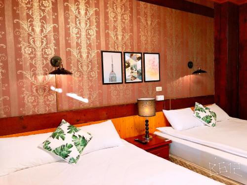 two beds in a hotel room with pictures on the wall at Sun Moon Heart Hostel in Puli