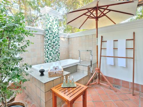 La salle de bains est pourvue d'une baignoire, d'une table et d'un parasol. dans l'établissement MonPanaNont Wellness Resort & Spa - SHA Extra Plus, à Mae Taeng