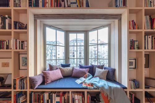 a library with a couch in front of a window at Bagatelle Gardenhouse in Budapest