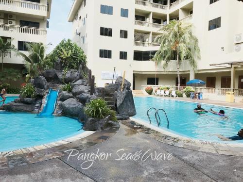 a pool at a hotel with people in the water at Sea & Wave #2 Coral Bay Apartment in Pangkor