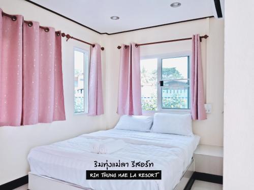 a small bedroom with pink curtains and a bed at ริมทุ่งแม่ลา รีสอร์ท Rim-Thung-Mae-La-Resort in Sing Buri