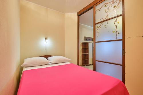 1 dormitorio con cama rosa y ventana en ОК! Никитина, 20 №2, en Tomsk
