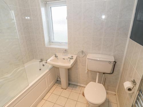 a white bathroom with a toilet and a sink at Happy Daze in Pwllheli