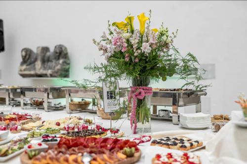 a table topped with plates of food and a vase of flowers at Hotel Silver in Osijek