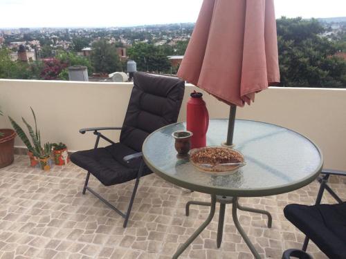 una mesa con sillas y una sombrilla en el balcón en Departamento entre cerros y cielo en Salta