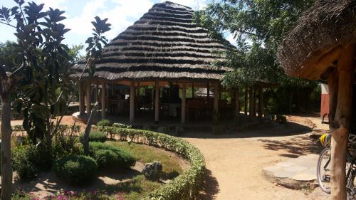 um edifício com telhado de palha e jardim em Heritage Safari Lodge em Pakwach East