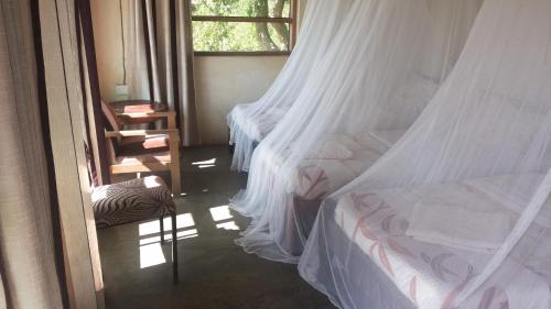 a bedroom with two beds with mosquito nets at Heritage Safari Lodge in Pakwach East