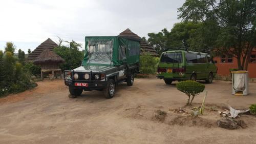 two green trucks parked on a dirt road at Heritage Safari Lodge in Pakwach East