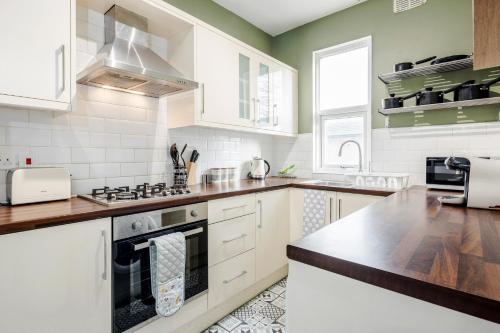 a kitchen with white cabinets and a stove top oven at Luxury Apartment 2bed & Parking - East London - by Damask Homes in Ilford