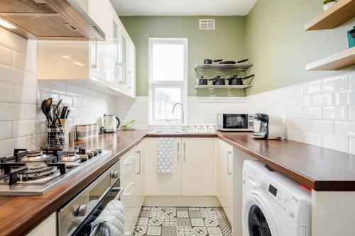 a kitchen with a stove and a washer and dryer at Business & Leisure 2 BR & Parking by Damask Homes in Ilford