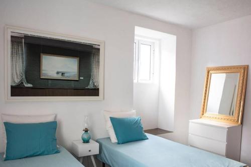 a bedroom with two blue beds and a mirror at Casa das Artes in Serreta